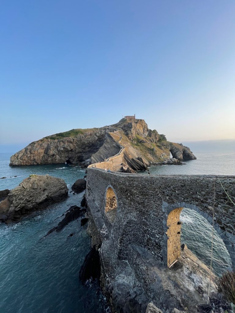 a stone structure on a cliff over the ocean. Mejores ciudades para inmigrantes en España