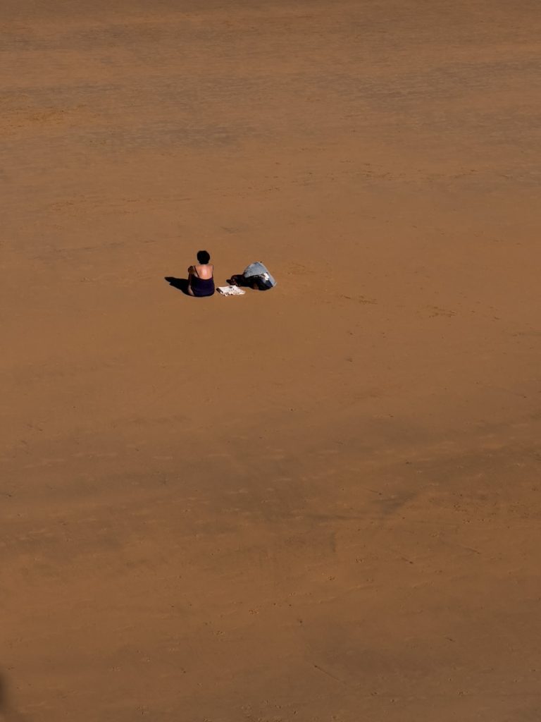 a person laying on the ground in the middle of a fieldMejores ciudades para inmigrantes en España