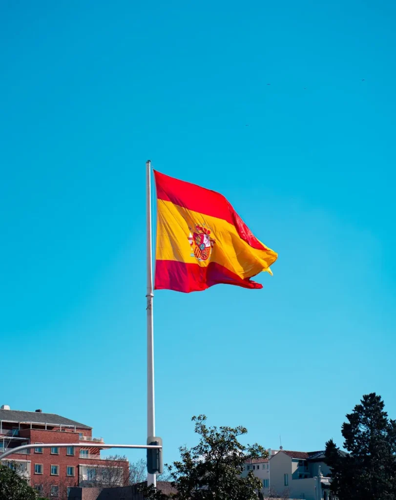 The Spanish national flag waving against a clear blue sky in Madrid, Spain.