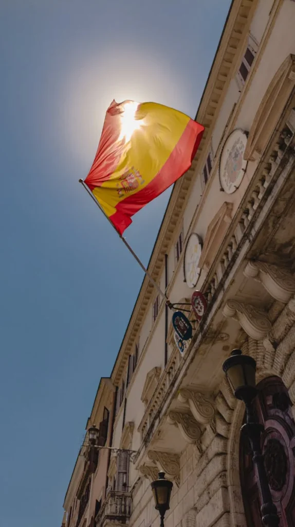 Spanish flag illuminated by the sun on a historical building in Rome.