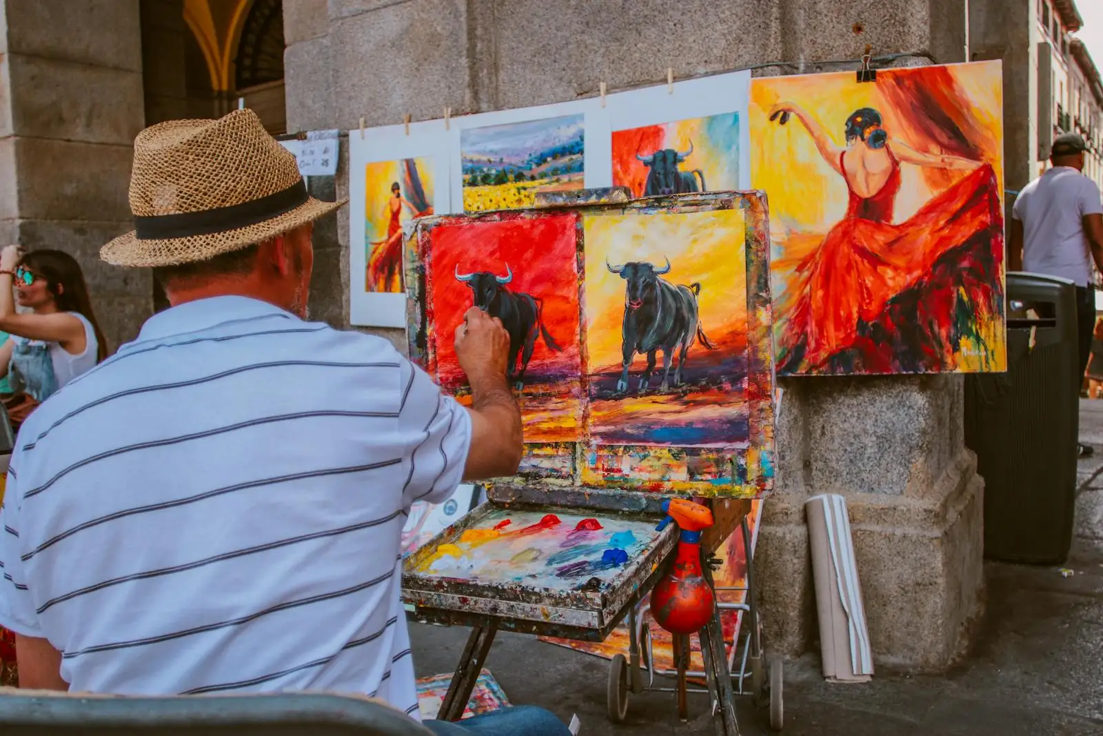 Street artist painting vibrant bull and flamenco dancer scenes in an outdoor market. Nacionalidad española, arraigo familiar, arraigo social, expediente extranjeria, como va lo mio