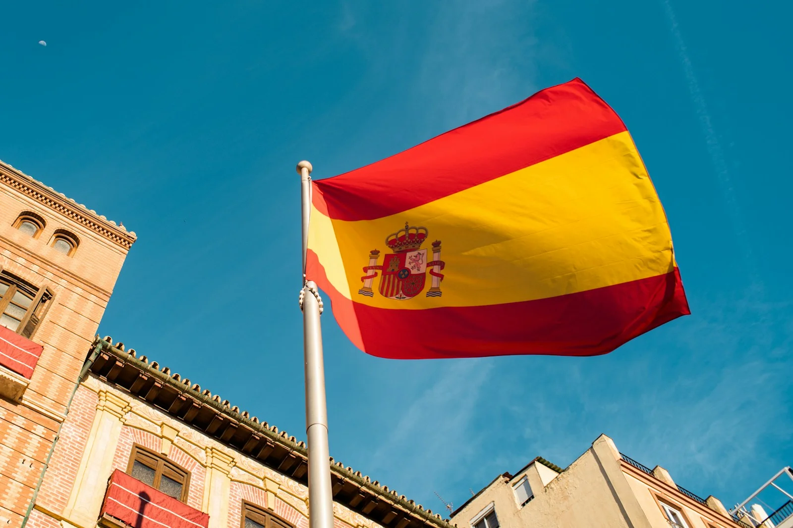bandera de españa ondeando en el cielo, nacionalizada española, arraigo familiar, viajar con tarjeta roja